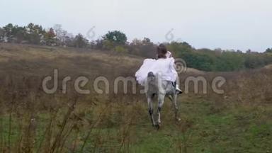 身穿婚纱的长发女子骑着奔腾的骏马穿过山谷